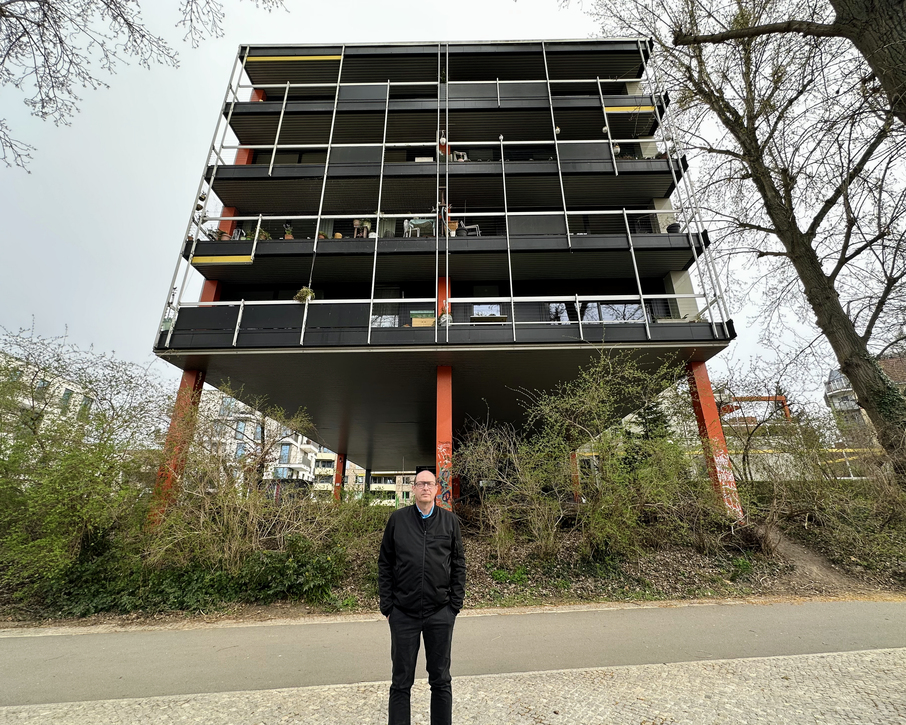 Henning stands in front of his home, a triangular structure.